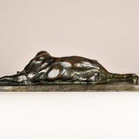 Alt text: Bronze sculpture of a lounging puma grooming itself