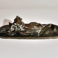 Alt text: Bronze sculpture of a lounging puma grooming itself