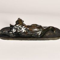 Alt text: Bronze sculpture of a lounging puma grooming itself