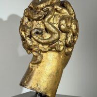 Alt text: Gilt bronze sculpture of a head of a boy with curly hair