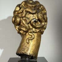 Alt text: Gilt bronze sculpture of a head of a boy with curly hair