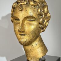Alt text: Gilt bronze sculpture of a head of a boy with curly hair