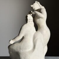 Alt text: Stylized, white sculpture of two women, one standing and one seated