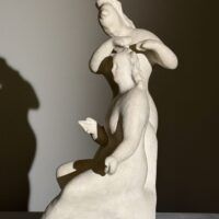 Alt text: Stylized, white sculpture of two women, one standing and one seated