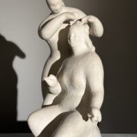 Alt text: Stylized, white sculpture of two women, one standing and one seated