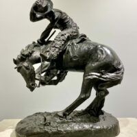 Alt text: Bronze sculpture of a cowboy atop a scared horse startled by a rattlesnake