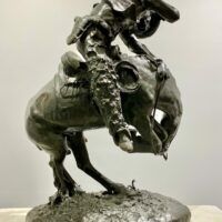 Alt text: Bronze sculpture of a cowboy atop a scared horse startled by a rattlesnake