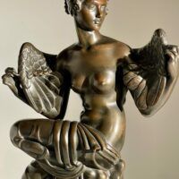 Alt text: Bronze sculpture of Philomela from Greek mythology, kneeling with wings growing from her back