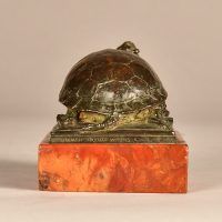 Alt text: Small bronze sculpture of a turtle eating a frog