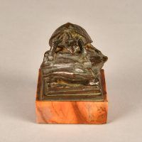 Alt text: Small bronze sculpture of a turtle atop a rock