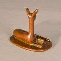 Alt text: Bronze sculpture of a doe lying down with her head and ears up, angled view