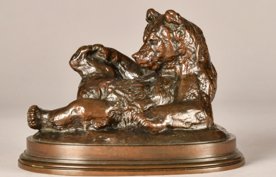 Alt text: Bronze sculpture of a bear lying on his back with feet up, angled view