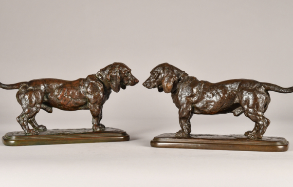 Alt text: Two bronze sculptures of standing Basset Hounds with tales extended