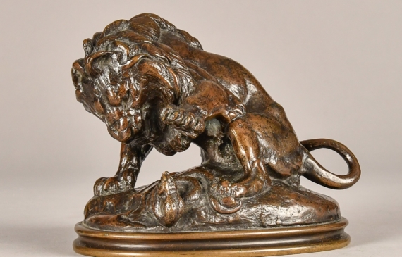 Alt text: Bronze sculpture of a lion fighting a serpent
