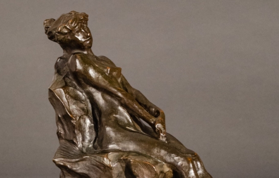 Alt text: Bronze sculpture of a nude woman sitting and reclining, side view