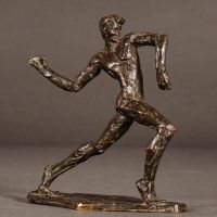 Alt text: Small bronze sculpture of an athlete caught in motion throwing with right arm, angled view