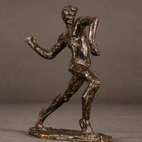 Alt text: Small bronze sculpture of an athlete caught in motion throwing with right arm, angled view