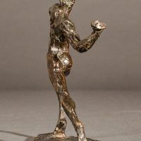 Alt text: Small bronze sculpture of an athlete caught in motion throwing with right arm, angled view