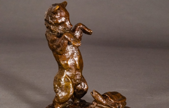 Alt text: Bronze sculpture of a bear standing on his hind legs scaring a turtle, angled view