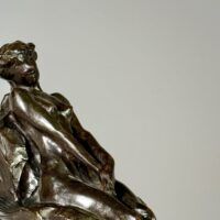 Alt text: Bronze sculpture of a nude woman sitting and reclining