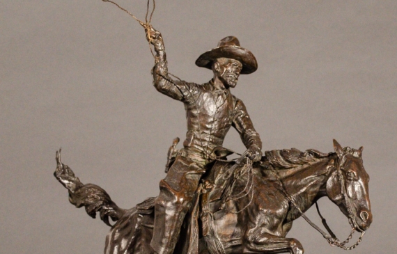 Alt text: Bronze sculpture of a cowboy with a lasso riding a horse jumping over a cactus