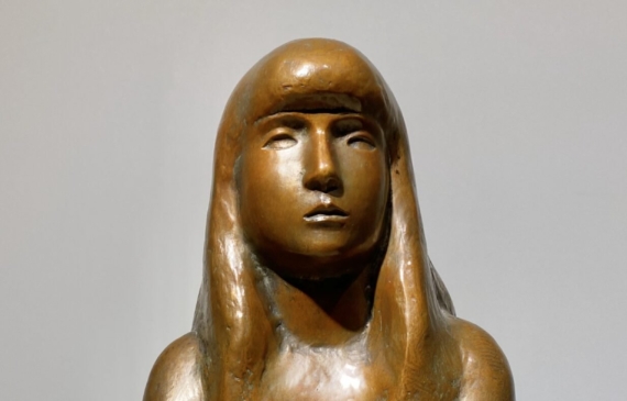 Alt text: Bronze sculpture of a girl with crossed arms, frontal view