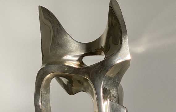 Alt text: Polished bronze sculpture of an abstract cat head, frontal view