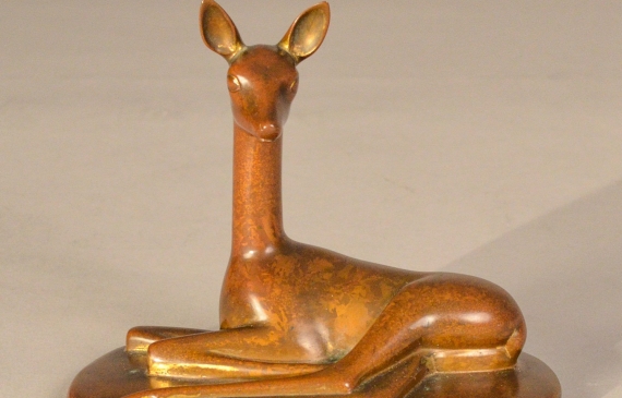 Alt text: Bronze sculpture of a doe lying down with her head and ears up, frontal view