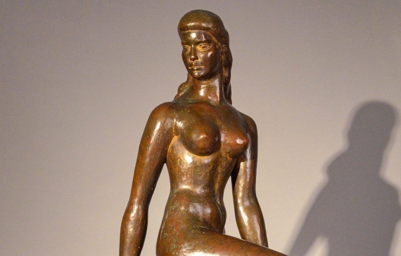 Alt text: Bronze sculpture of a nude dancer kneeling with one leg on the ground, holding a shawl behind her, frontal view