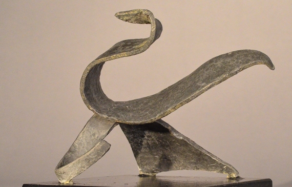 Alt text: Abstract soldered lead sculpture atop a wooden base resembling a swan, angled view