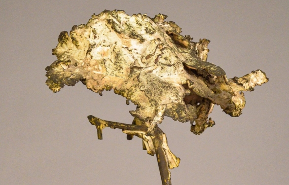 Alt text: Welded bronze sculpture shaped like a tree mounted on a slag block, angled view