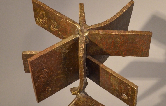 Alt text: Welded steel sculpture with many panels or blades, resembling a fan, frontal view