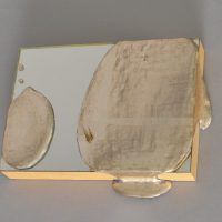Alt text: Mirror with silver leaf splotches dropped onto it, fixed to wood