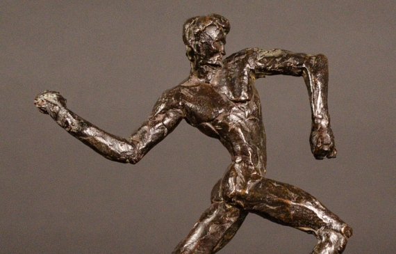 Alt text: Small bronze sculpture of an athlete caught in motion throwing with right arm