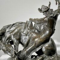 Alt text: Bronze sculpture of a man on a horse with a whip in his hand