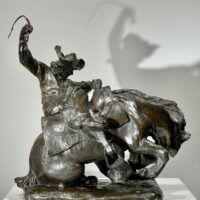 Alt text: Bronze sculpture of a man on a horse with a whip in his hand