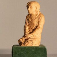 Alt text: Plaster sculpture of a kneeling girl