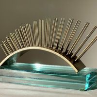 Alt text: metal sculpture with spikes on glass base