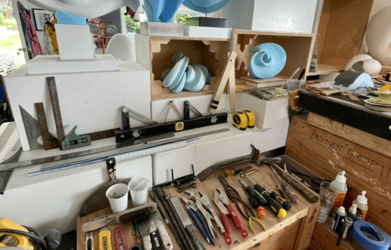 Alt text: photo of an artist's studio with tools and unfinished sculptures