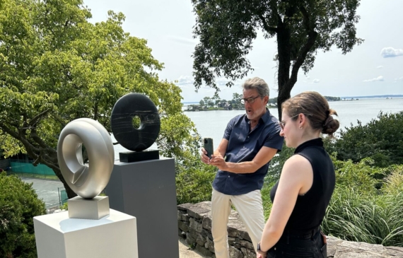 Alt text: two people standing outside with sculptures