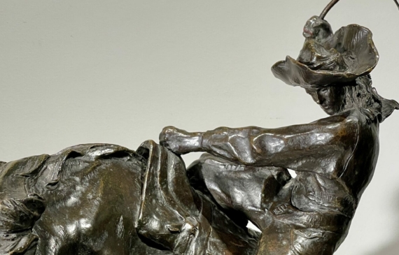 Alt text: Bronze sculpture of a man on a horse with a whip in his hand