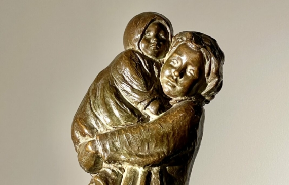 Alt text: Bronze sculpture of a young woman carrying her baby in 1910s clothing