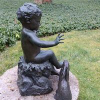 Alt text: Bronze outdoor sculpture of a child with two rabbits