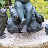 Alt text: Bronze outdoor sculpture of a child with two rabbits