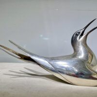 Alt text: Sculpture of a bird with a silver finish