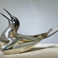 Alt text: Sculpture of a bird with a silver finish