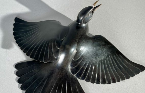 Alt text: Bronze sculpture of a bird with wings spread