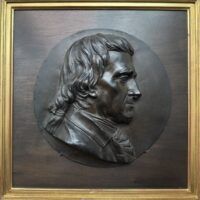 Alt text: Bronze relief portrait of a man's side profile