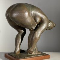 Alt text: Bronze sculpture of a nude woman bending over