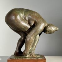 Alt text: Bronze sculpture of a nude woman bending over